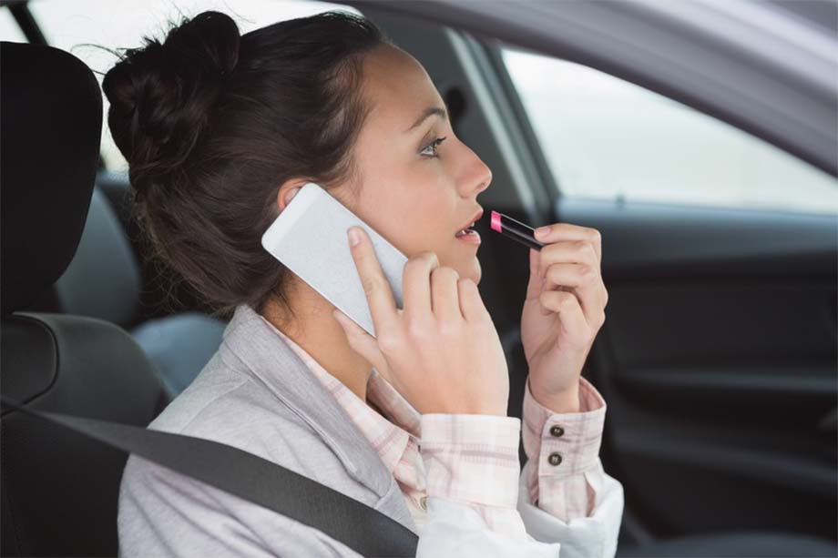 Woman having a phone call while putting on lipstick